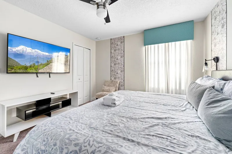 Bedroom with a pale headboard and television